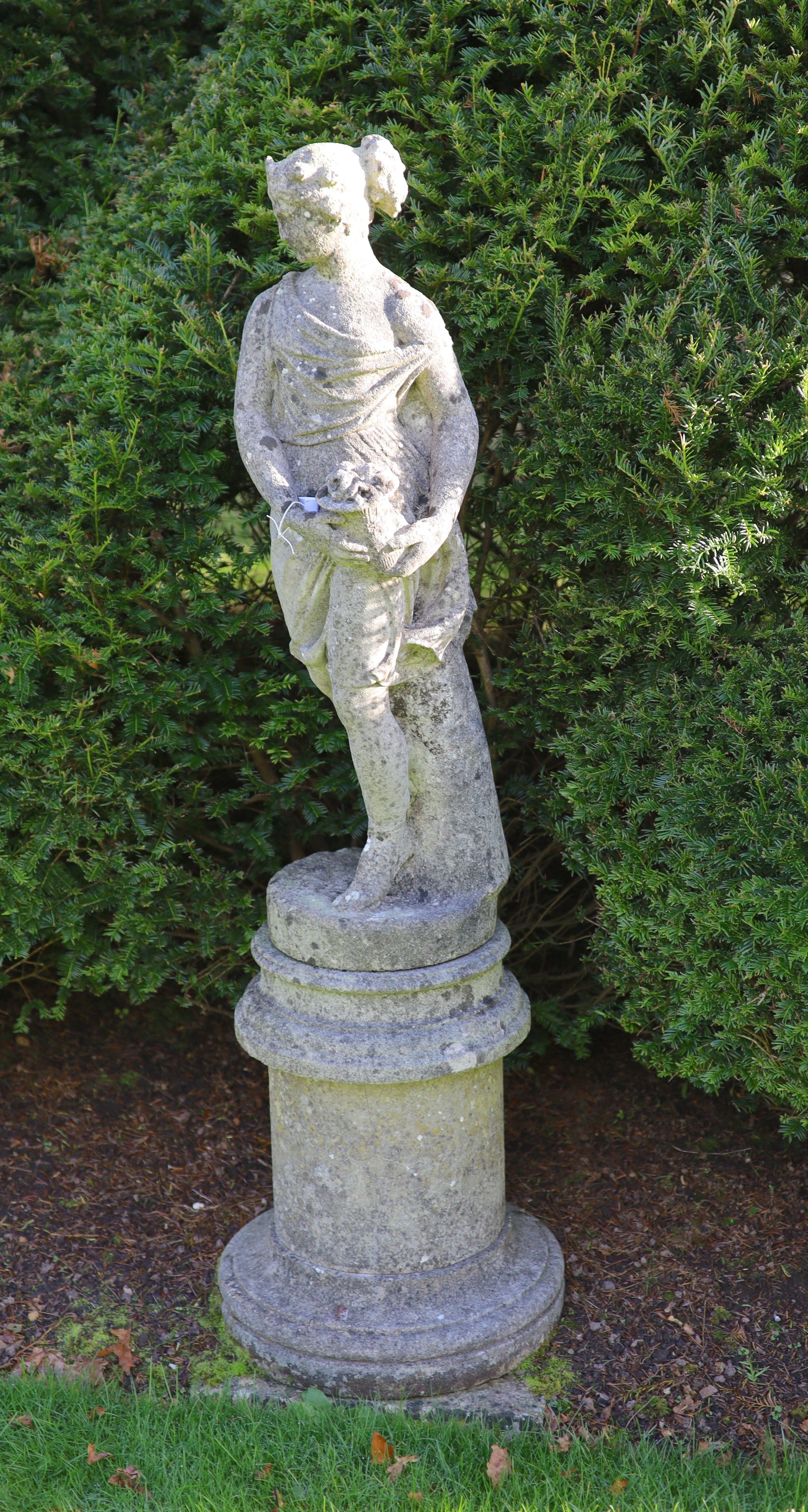 A reconstituted stone garden statue modelled as Flora, on turned socle, height overall 154cm